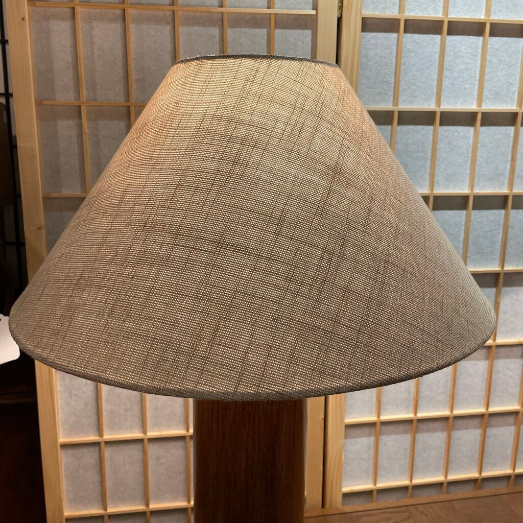 Textured lampshade on a wooden stand with a wooden screen background