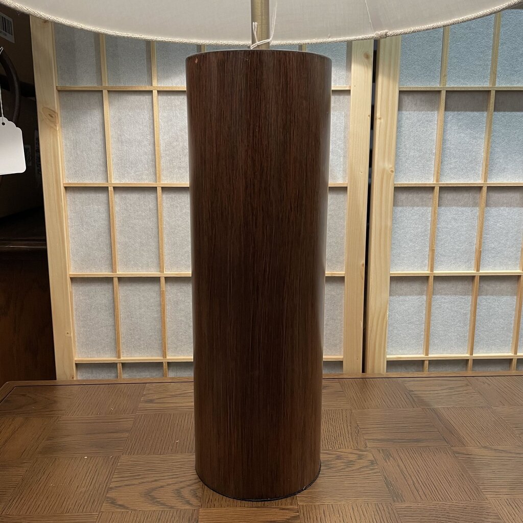 Wooden cylindrical object on a wooden floor with a windowed wall in the background