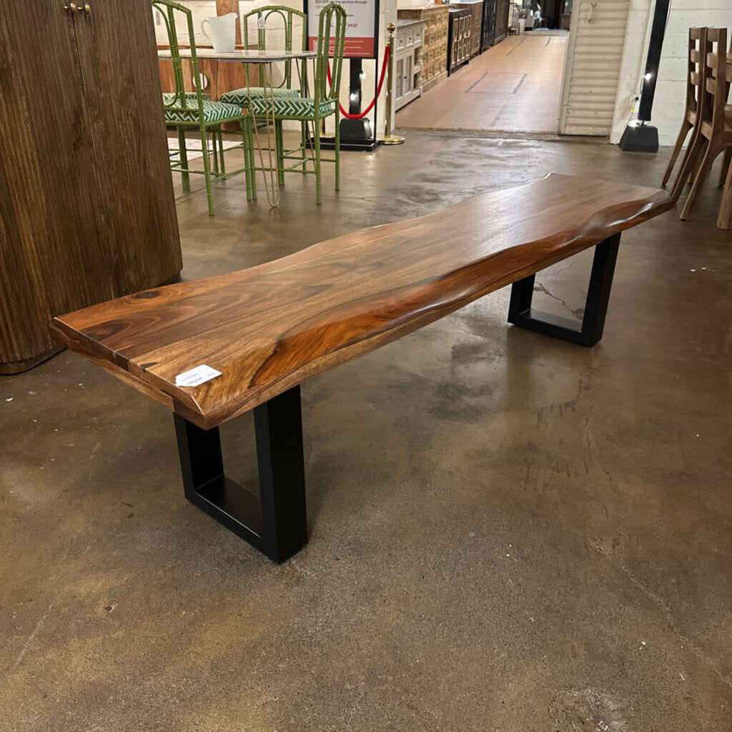 Wooden bench with a live-edge design on a concrete floor