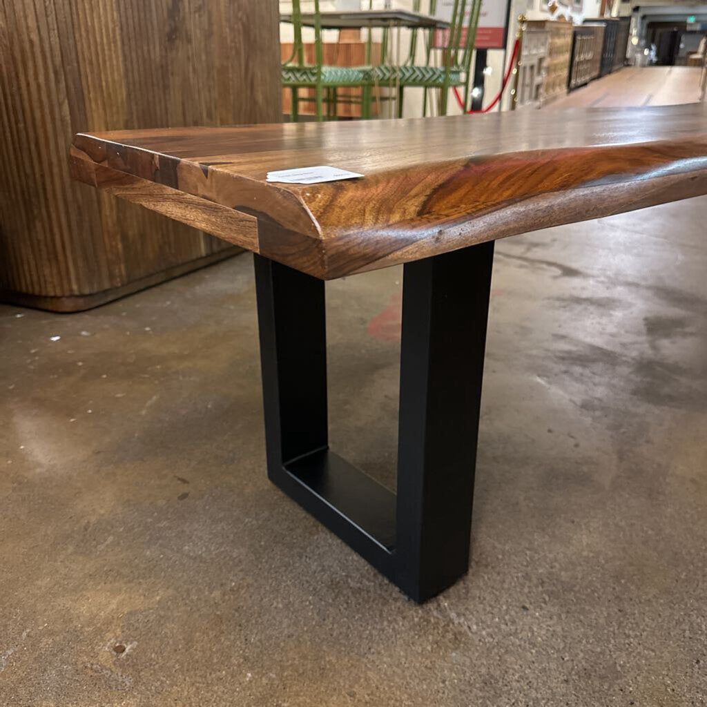 Wooden table with black metal legs on a concrete floor
