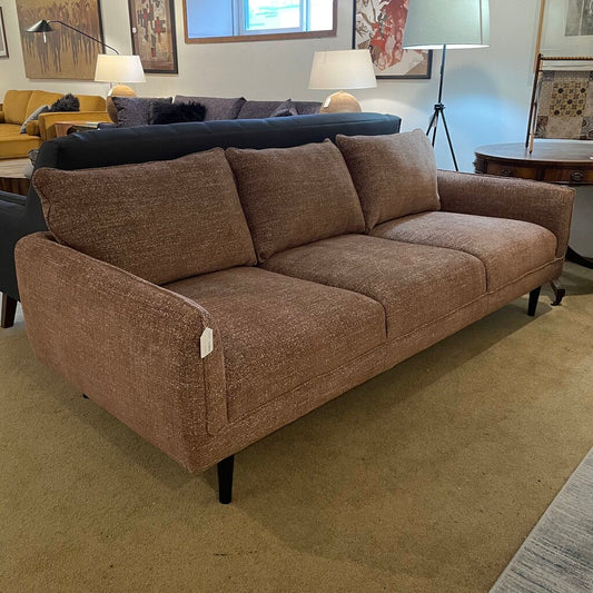 This mid-century modern (MCM) inspired sofa features a streamlined, low-profile silhouette with a classic three-cushion design. The piece is upholstered in a textured, woven fabric in a warm camel or tawny brown hue, characteristic of retro "mod" aesthetics.