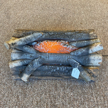 Stack of firewood with a glowing ember on a brown surface