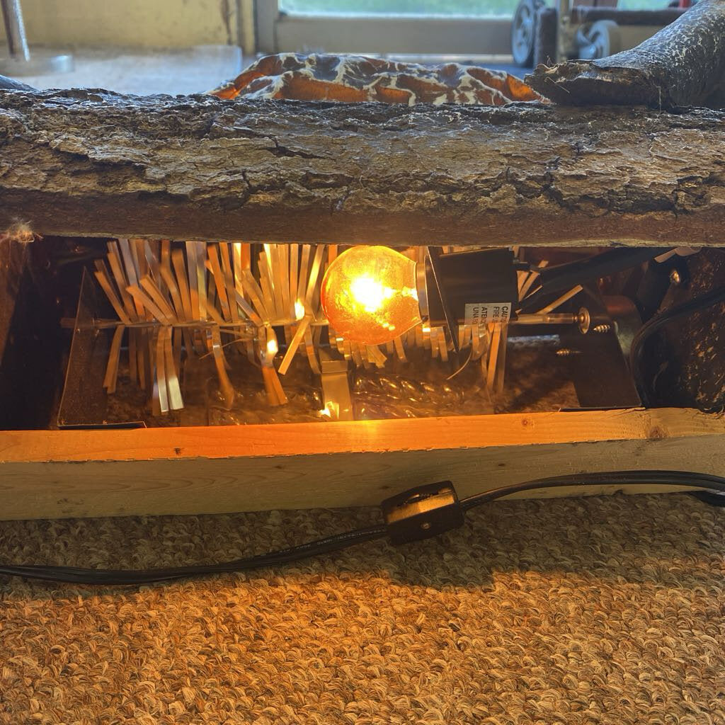 Wooden lamp with a light bulb inside, placed on a textured surface.