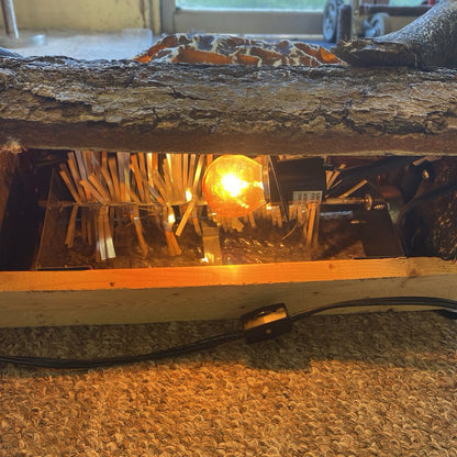 Wooden lamp with a light bulb inside, placed on a textured surface.