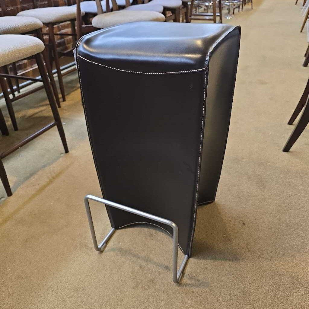 Black bar stool with a metal base on a beige carpeted floor.