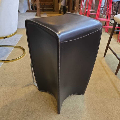 Black leather stool on a carpeted floor with chairs in the background