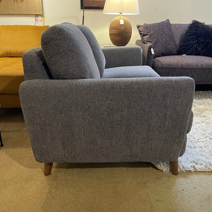 Gray sofa in a showroom with other furniture and decor items.
