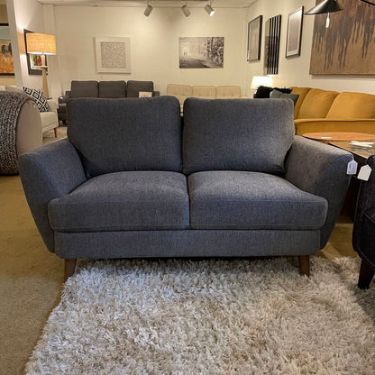 Gray sofa in a showroom with other furniture and decor items.