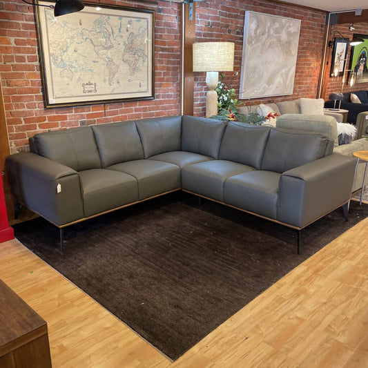 Gray sectional sofa in a living room with brick walls and framed maps.