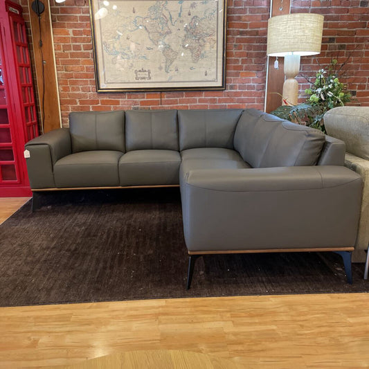 Gray sectional sofa in a room with a brick wall and decorative elements.