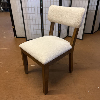 Chair with white cushioned seat and backrest on a brown floor.