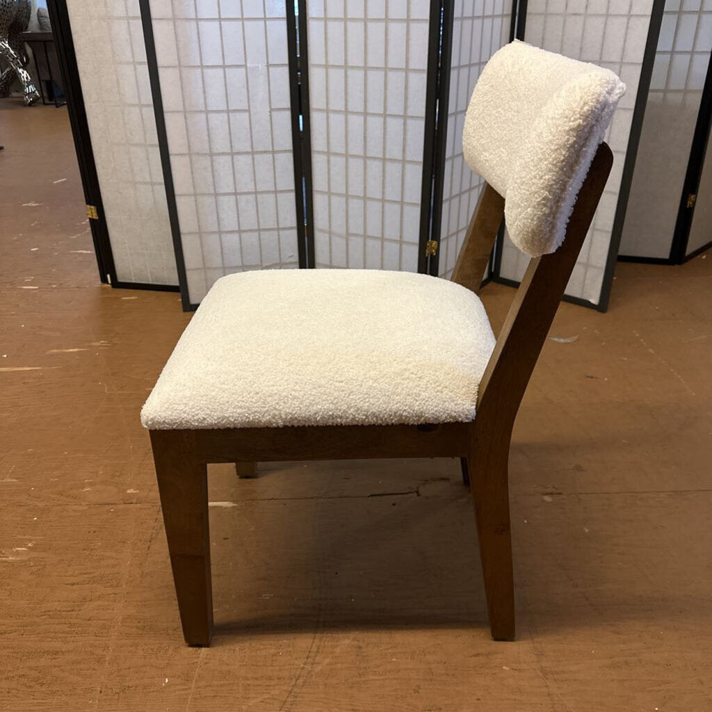 Chair with white cushioned backrest and seat on a brown floor.