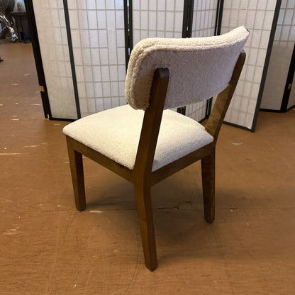 Wooden chair with a cushioned backrest and seat on a wooden floor.