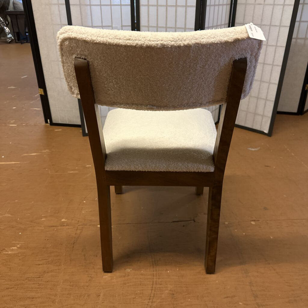 Chair with a beige cushioned backrest and seat on a wooden floor.