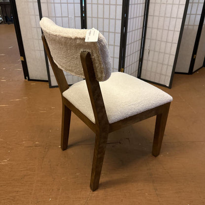Wooden chair with beige cushioned seat and backrest on a brown floor.