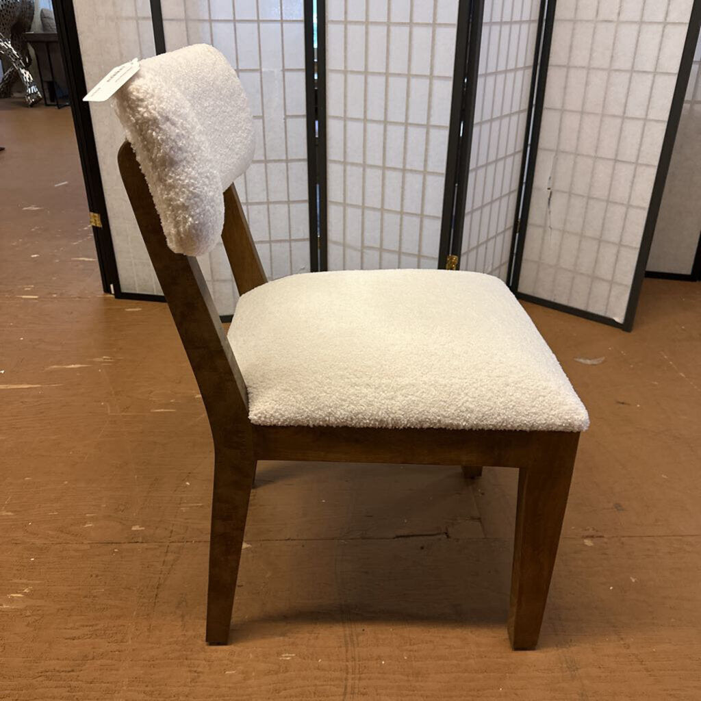 Wooden chair with white cushioned seat and backrest on a brown floor.