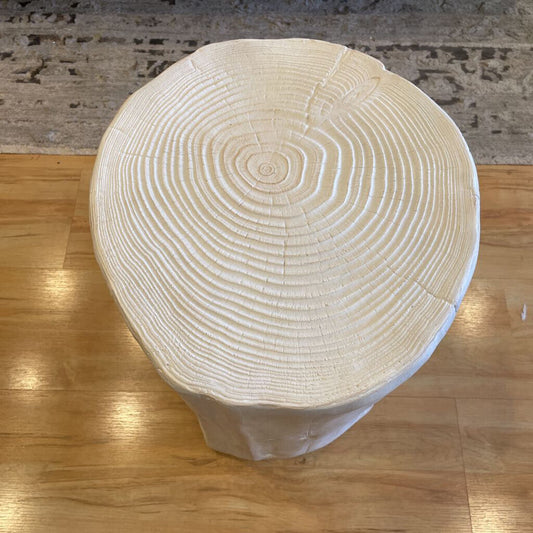Wooden stool with visible grain and rings on a wooden floor.