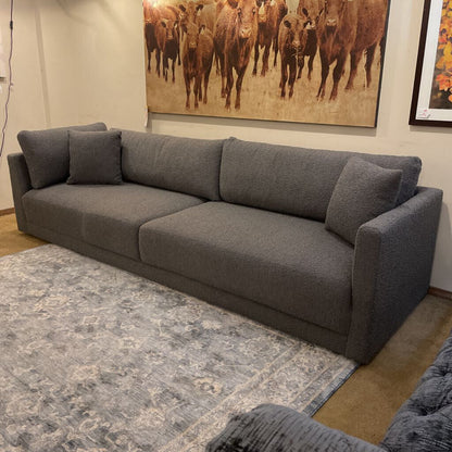 Gray sectional sofa in a room with a large painting of cows on the wall.