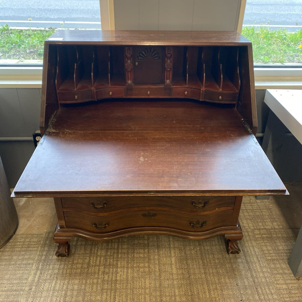 Wooden desk with hinged top in a room with windows