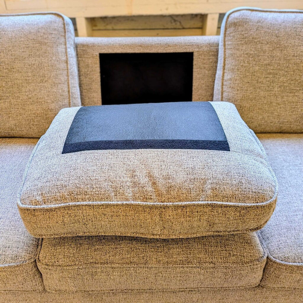 Brown upholstered chair with a blue cushion on a wooden floor.