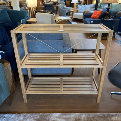 Wooden shelf in a furniture store with blue chairs and other items in the background