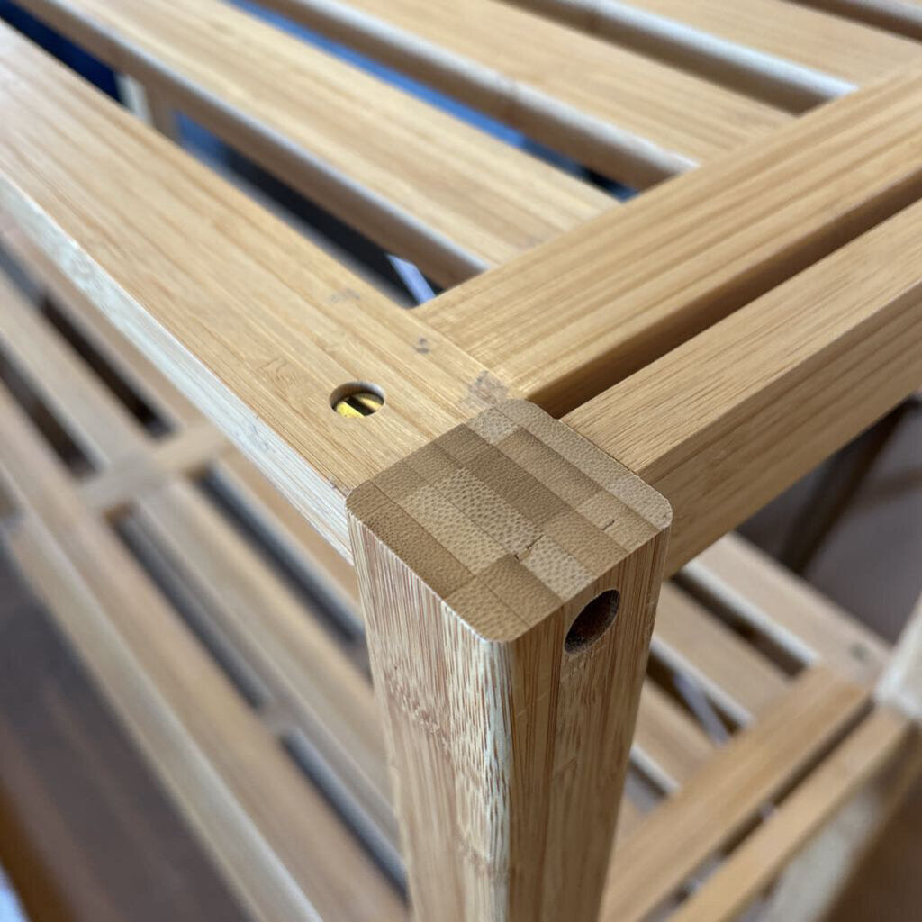 Close-up of a wooden slatted chair with a focus on the corner joint.