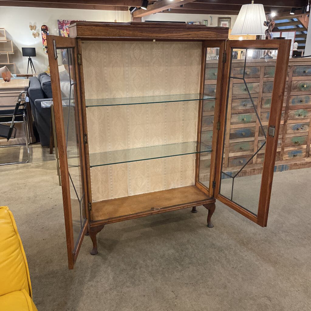 Wooden display cabinet with glass doors in a room setting