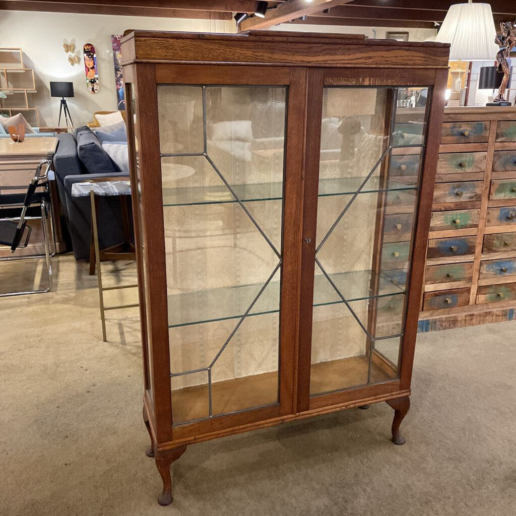 Wooden display cabinet with glass doors in a room setting