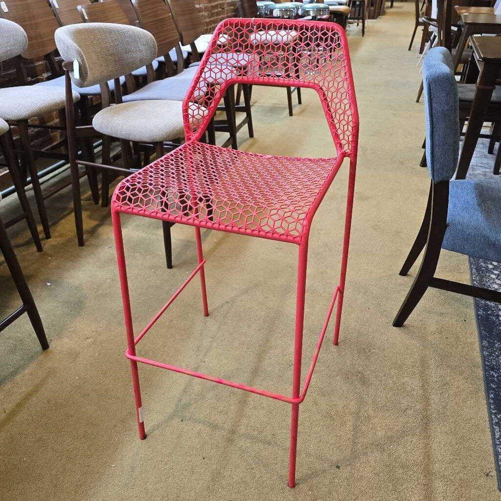 Red metal chair in a room with other chairs and tables