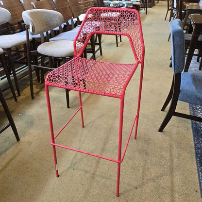 Red metal chair in a room with other chairs and tables