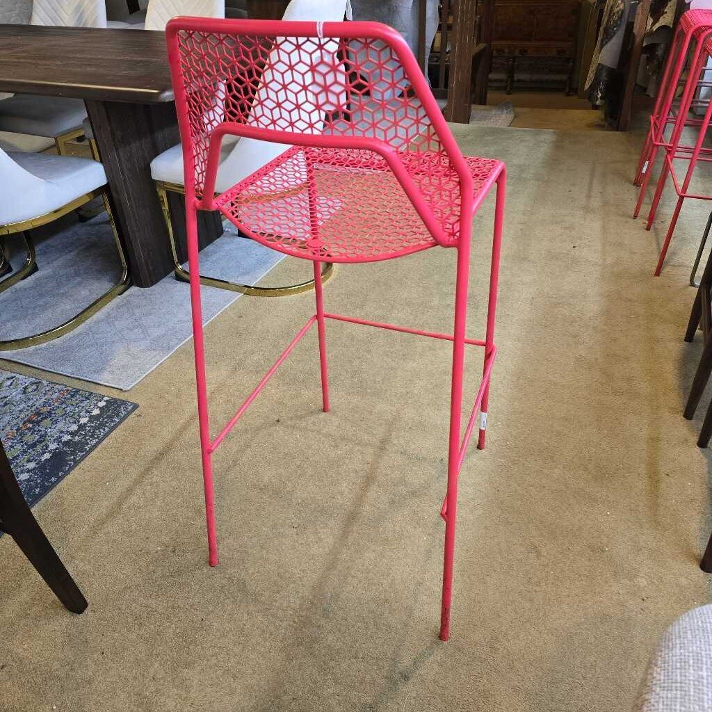 Pink metal chair on a carpeted floor with other furniture in the background