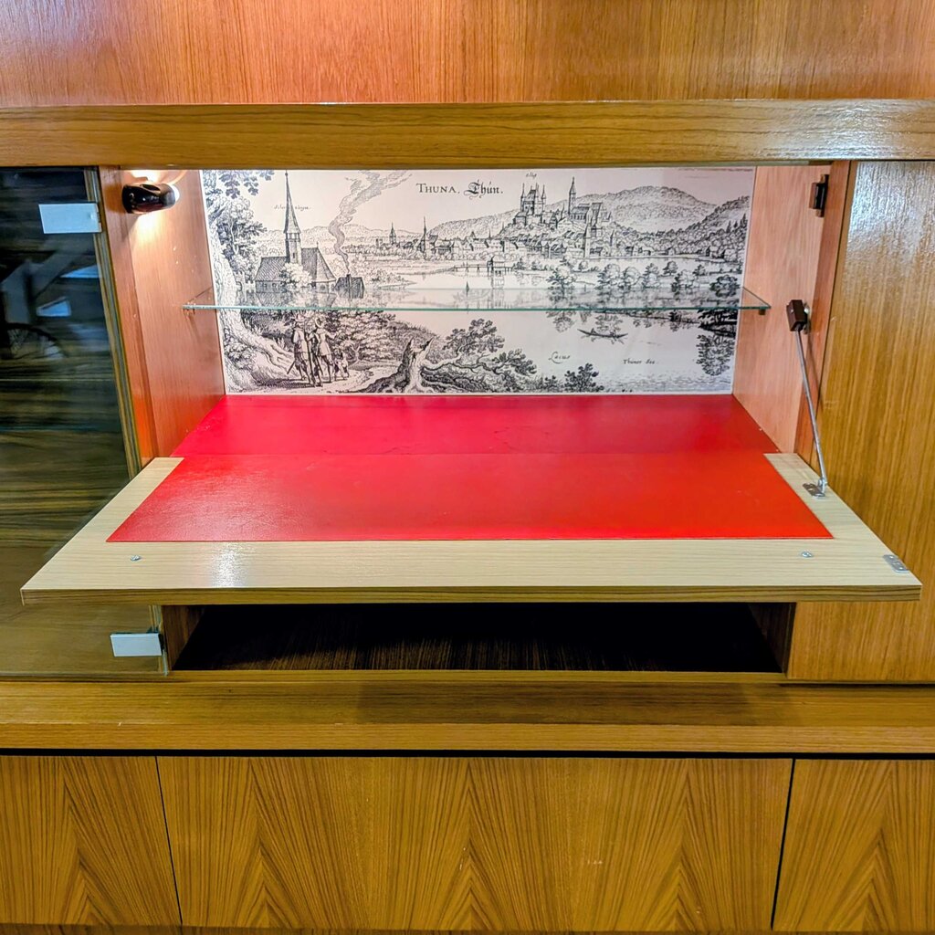 Wooden cabinet with a red interior and printed design on the door.