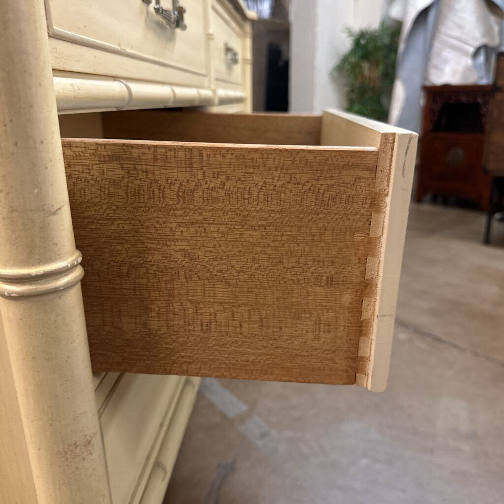 Open drawer of a beige dresser with a textured interior.