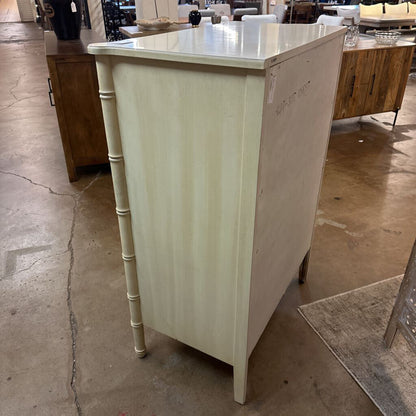 Light-colored kitchen island with bamboo-style legs in a showroom setting