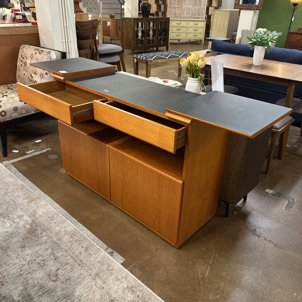 Wooden kitchen island with open drawers in a showroom setting