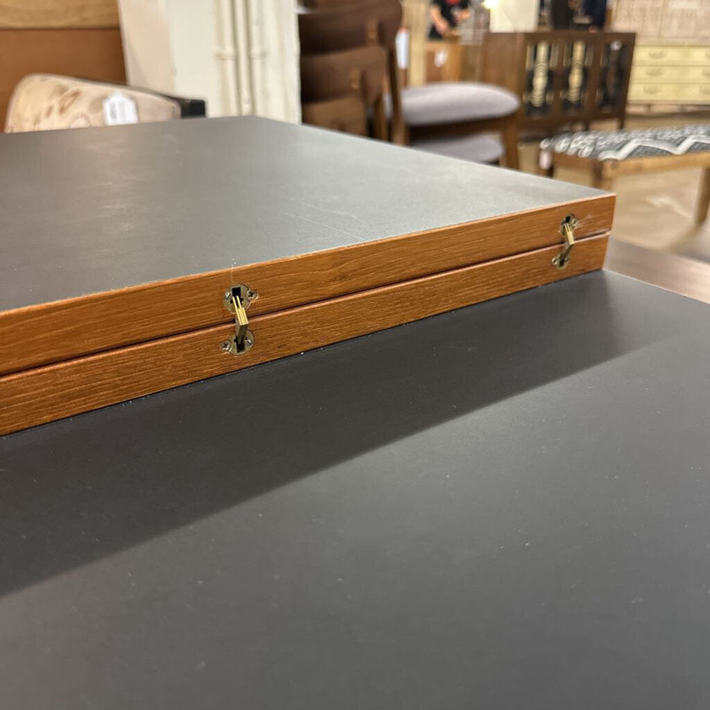 Wooden box with a gray lid on a dark surface, blurred furniture background