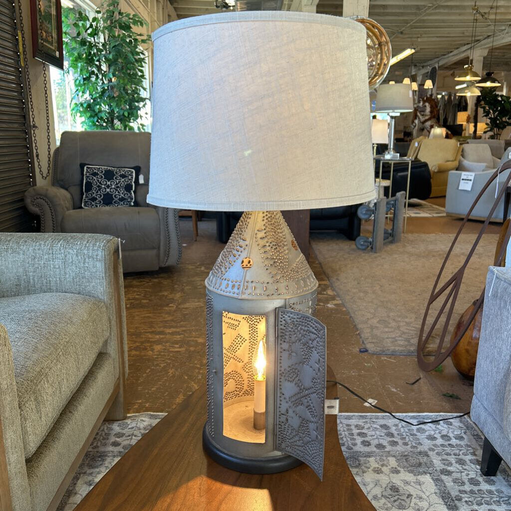 Decorative table lamp with a white shade on a wooden table in a furniture store.