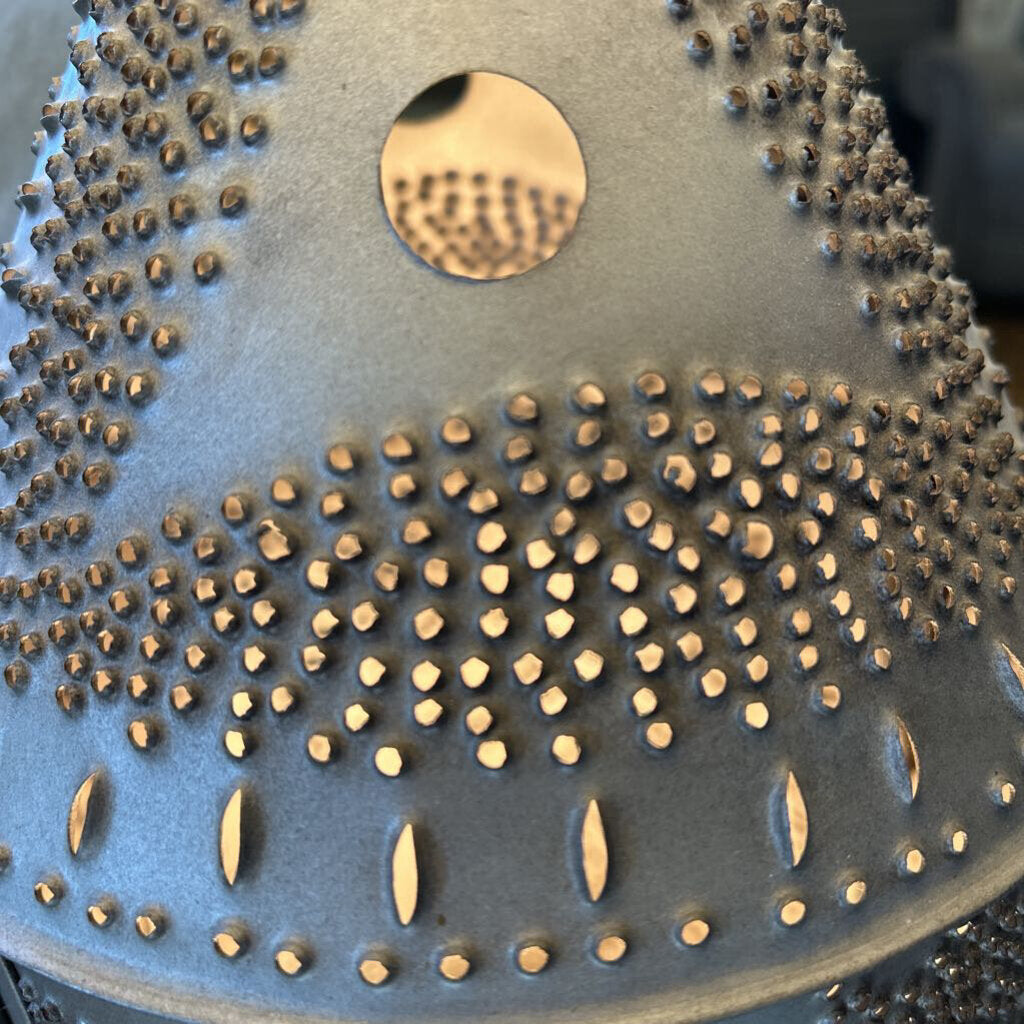 Close-up of a textured surface with small raised elements and a circular metallic feature.