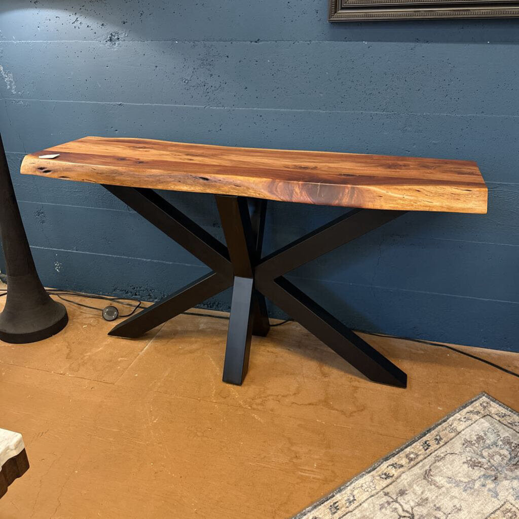 Wooden table with black metal legs against a blue wall.