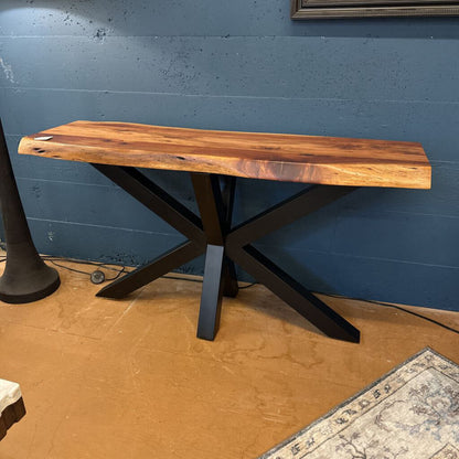 Wooden table with black metal legs against a blue wall.