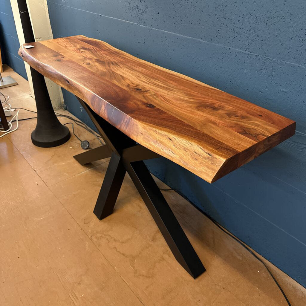 Wooden console table with black metal legs against a blue wall.