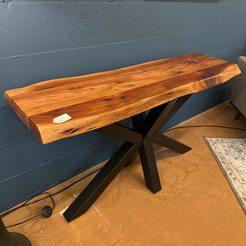 Wooden console table with black metal legs against a blue wall.