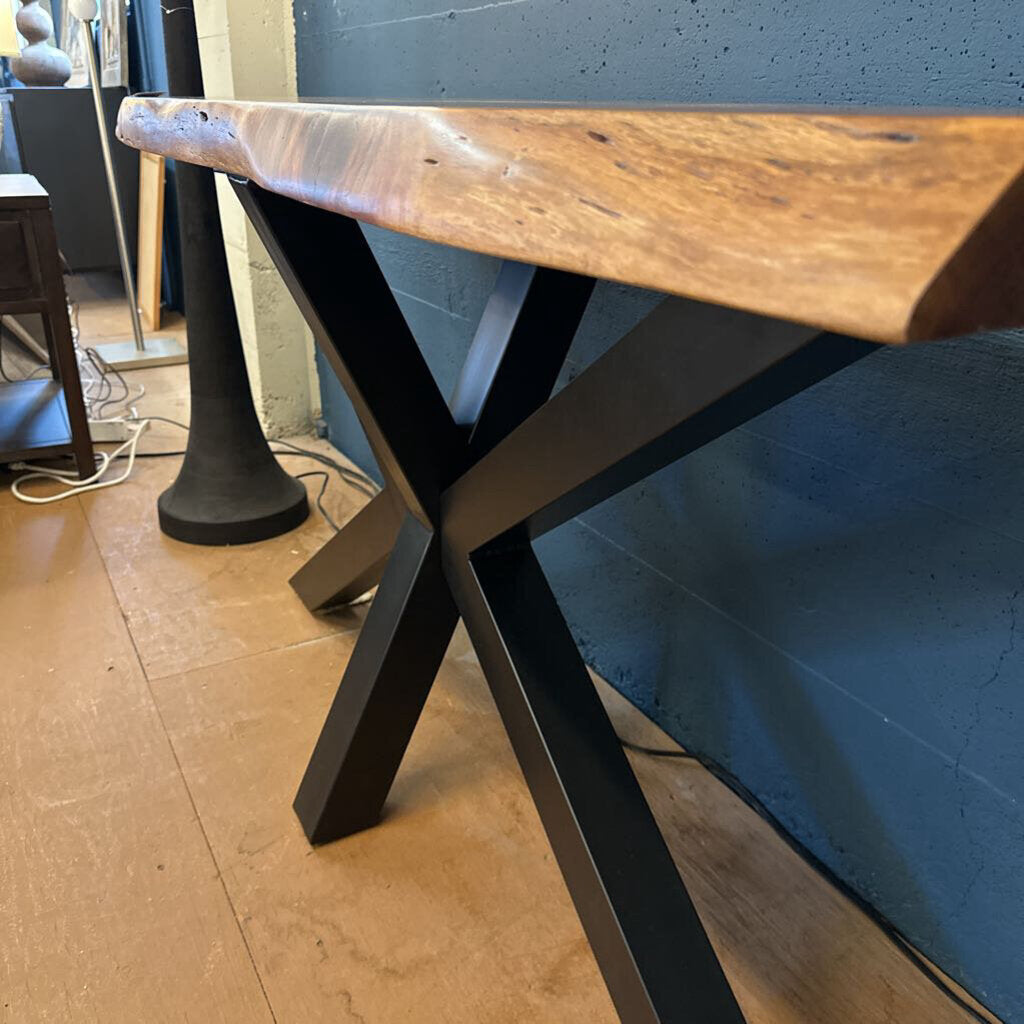 Wooden table with black metal legs on a wooden floor.