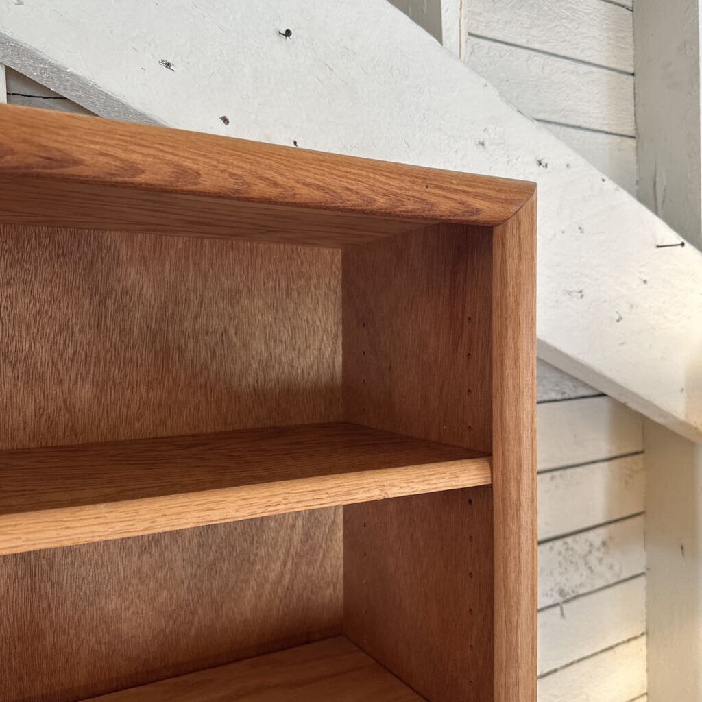 Wooden shelf under a staircase with light-colored wooden floor and wall.