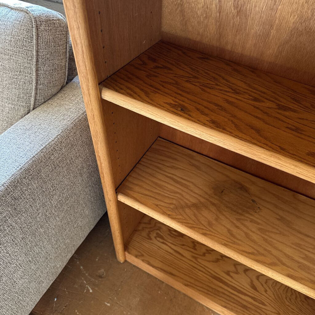 Wooden bookshelf next to a gray sofa