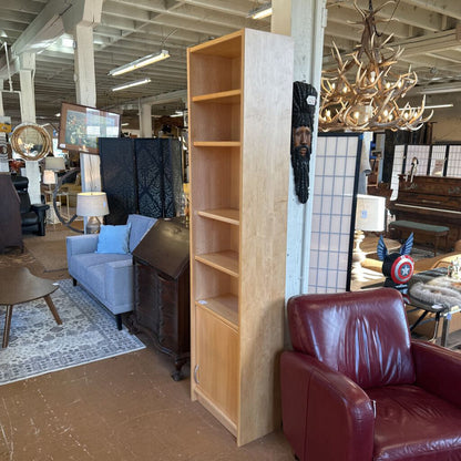 Furniture store with a tall wooden bookshelf, red leather chair, and various decor items.