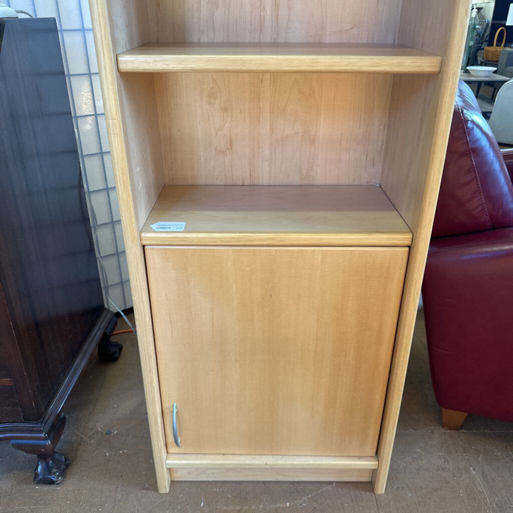 Wooden bookshelf with a cabinet door in a room setting