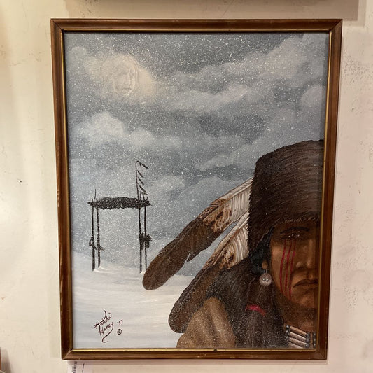 Framed artwork of a Native American figure with a wooden structure and cloudy sky.