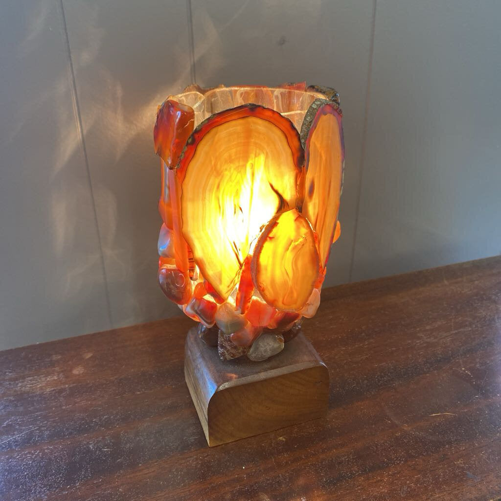 Decorative lamp with a wooden base and glass shade on a wooden surface.