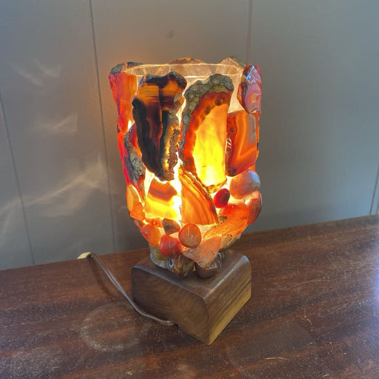 Decorative lamp with a wooden base and colorful glass shade on a wooden surface.